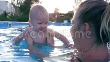 快乐的小男孩和他的妈妈在蓝水游泳池里嬉笑打闹